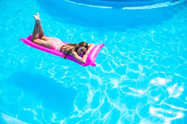 Το κορίτσι που επιπλέει σε ένα φουσκωτό στρώμα στην πισίνα — Φωτογραφία Αρχείου