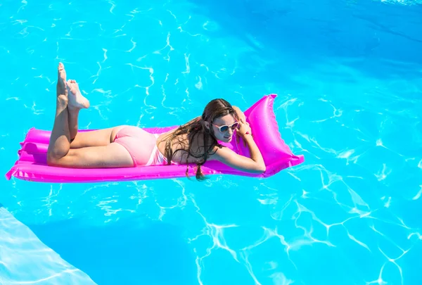 Дівчина плаває на надувному матраці в басейні — стокове фото