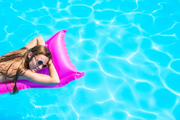 Das Mädchen schwimmt auf einer aufblasbaren Matratze im Pool — Stockfoto