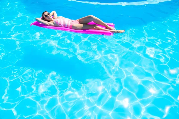 The girl floats on an inflatable mattress in the pool — Stock Photo, Image