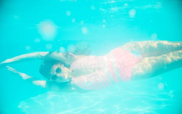 Chica joven en gafas de sol nadando bajo el agua — Foto de Stock