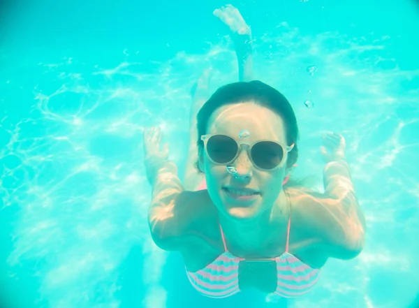Jeune fille en lunettes de soleil nageant sous l'eau — Photo