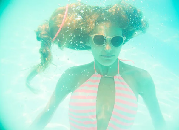 Junges Mädchen mit Sonnenbrille schwimmt unter Wasser — Stockfoto