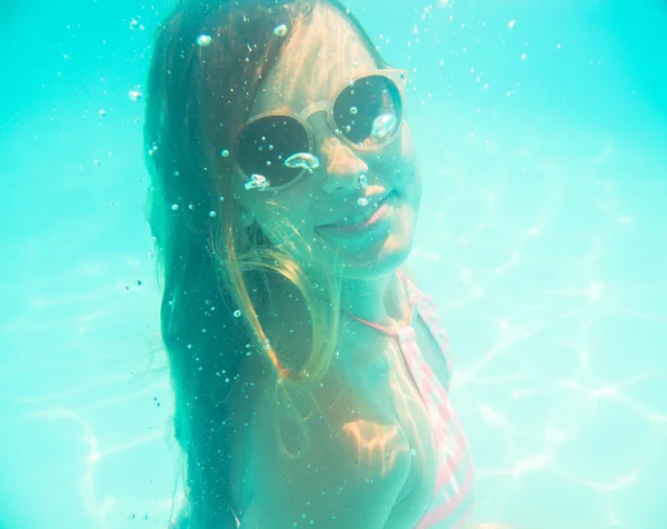 Jeune fille en lunettes de soleil nageant sous l'eau — Photo