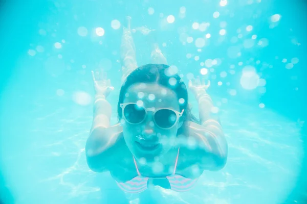Ung flicka i solglasögon simma under vattnet — Stockfoto