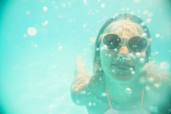 Giovane ragazza in occhiali da sole nuotare sott'acqua — Foto Stock