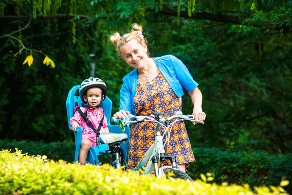 Mom on a bike with a small child, who wore a bicycle helmet and — Stock Photo, Image