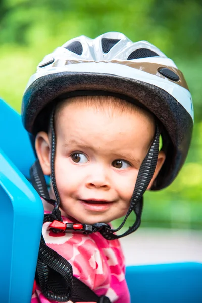 Bambina vestita con casco da bicicletta e si siede su un seggiolino per bicicletta — Foto Stock