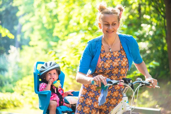 自転車のヘルメットを身に着けていた小さい子供が付いているバイクのお母さんと — ストック写真