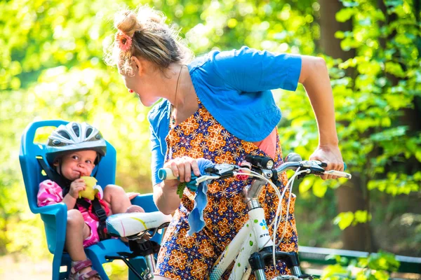 Mom on a bike with a small child, who wore a bicycle helmet and — Stock Photo, Image