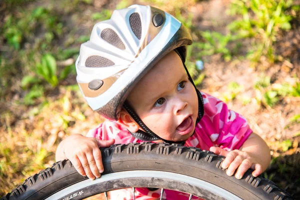 大きな自転車の車輪の近くに自転車ヘルメットの少女 — ストック写真