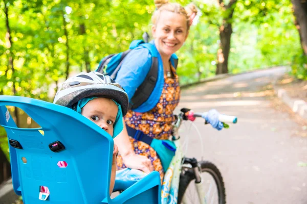 自転車のヘルメットを身に着けていた小さい子供が付いているバイクのお母さんと — ストック写真