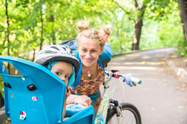 Mamma in bicicletta con un bambino piccolo, che indossava un casco da bicicletta e — Foto Stock