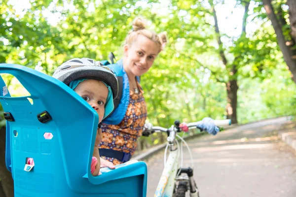 Mom on a bike with a small child, who wore a bicycle helmet and — Stock Photo, Image