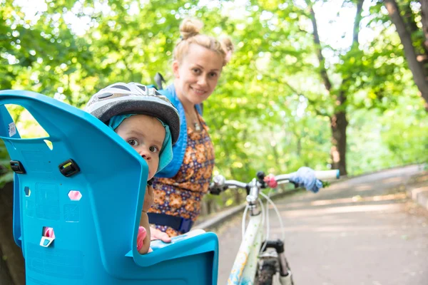 Mom on a bike with a small child, who wore a bicycle helmet and — Stock Photo, Image