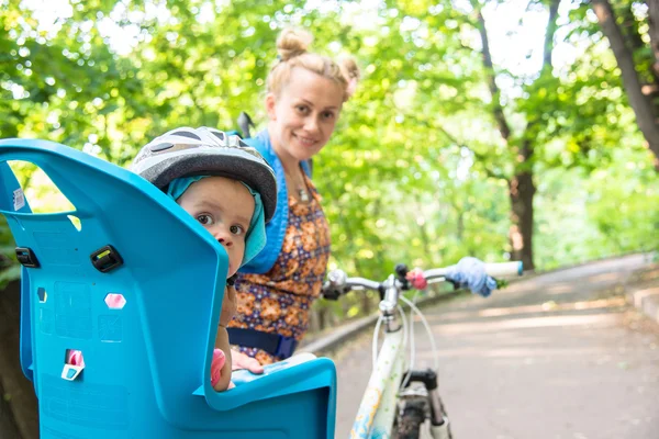 自転車のヘルメットを身に着けていた小さい子供が付いているバイクのお母さんと — ストック写真