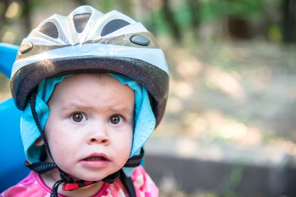 Bambina vestita con casco da bicicletta e si siede su un seggiolino per bicicletta — Foto Stock