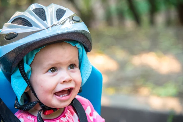 Bambina vestita con casco da bicicletta e si siede su un seggiolino per bicicletta — Foto Stock