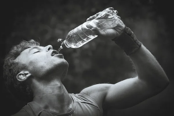 Mann trinkt Wasser, nachdem er Ufer überquert hat. Schwarzweiß-Photogra — Stockfoto