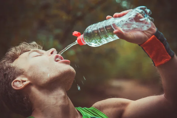 Чоловік п'є воду після пробігу банків — стокове фото