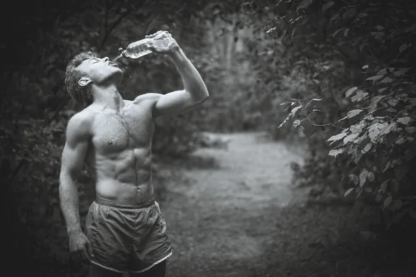 Homem bebendo água depois de correr bancos. Fotogra preto e branco — Fotografia de Stock