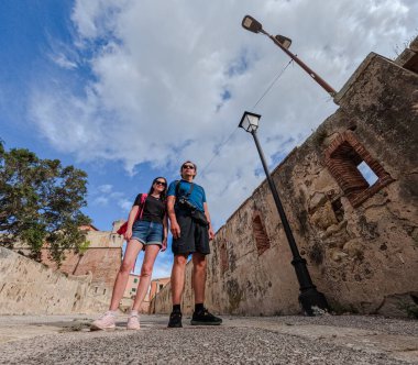 Tarihi duvarlar arasında eski taş caddede yürüyen iki turist..