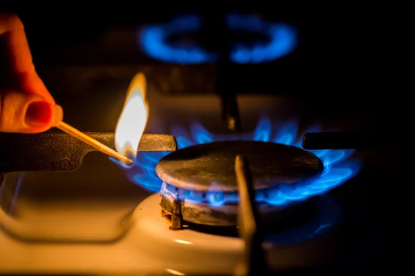 stock image Hand with a match ignites the gas stove