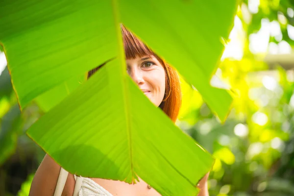 The girl is behind the palm leaf — Stock Photo, Image