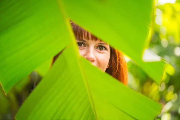 The girl is behind the palm leaf — Stock Photo, Image