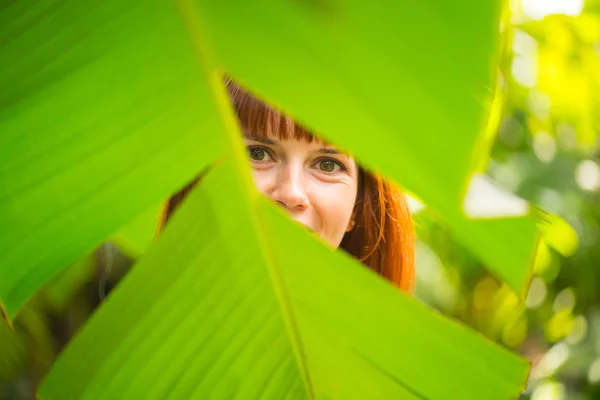 The girl is behind the palm leaf — Stock Photo, Image