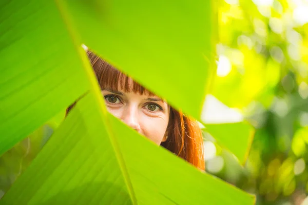 The girl is behind the palm leaf — Stock Photo, Image