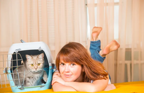 Mädchen auf dem Bett liegend, neben einem tragbaren Käfig, in dem sich — Stockfoto