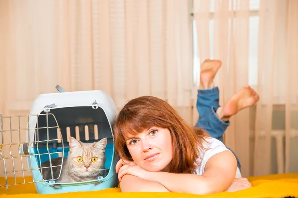 Chica acostada en la cama, junto a una jaula portátil en la que hay — Foto de Stock