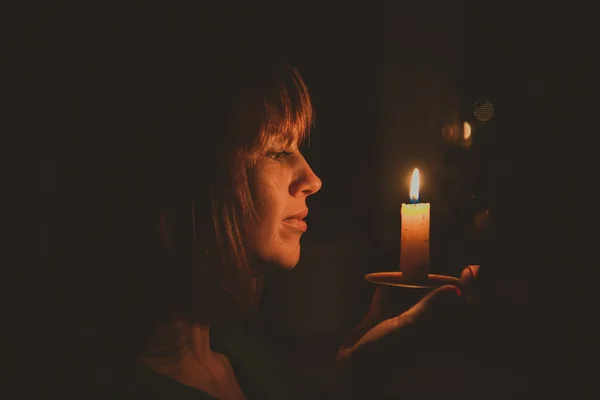Она зажгла свечу в темной комнате. — стоковое фото