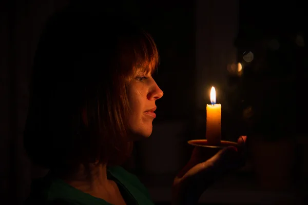 She shines a candle in a dark room — Stock Photo, Image