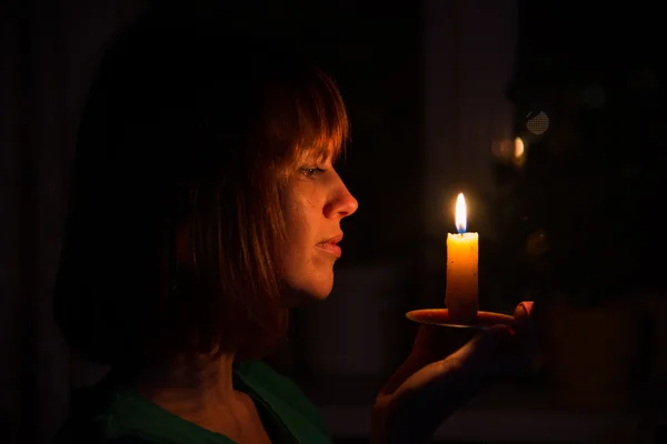 Sie leuchtet eine Kerze in einem dunklen Raum — Stockfoto