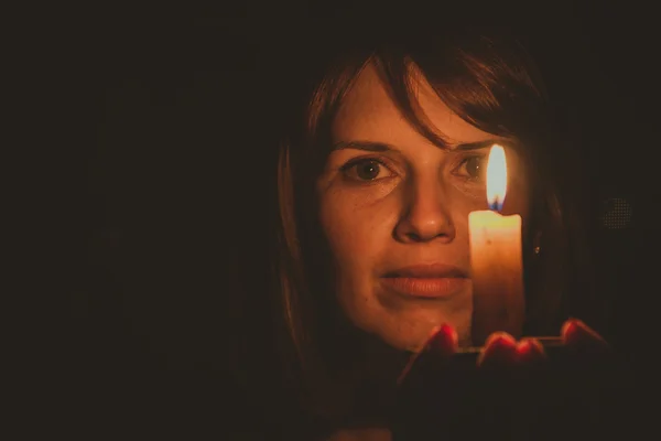 Ela brilha uma vela em um quarto escuro — Fotografia de Stock