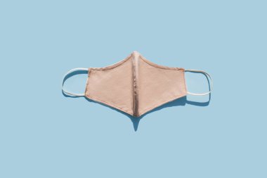 Solunum ya da cerrahi el yapımı pamuk yüz maskesi. Mavi arka planda Coronavirus veya COVID-19 koruması. Salgın ya da salgın hastalık konsepti. Düz konum, üst görünüm.