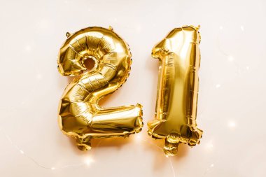 Altın folyo balonları 21 numara. Bej arka planda 21 numara. Mutlu Noeller, mutlu yıllar 2021, doğum günü konsepti. Parti dekorasyonu. Düz yatış, üst görünüm.