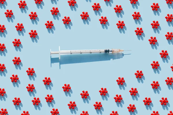 Creative pattern from Red models of coronavirus and syringe of blue background. Colorful concept of New Corona virus 2019-nCoV or COVID-19 vaccine. Flat lay, top view.