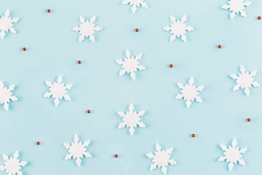Noel kompozisyonu. Kar tanelerinden yapılmış desen, mavi arka planda kırmızı süslemeler. Noel, kış, yeni yıl konsepti. Asgari düzeyde. Düz yatış, üst görünüm. 