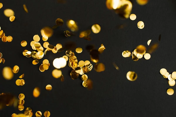 Gouden confetti op zwarte achtergrond. Feestelijke vakantie achtergrond. Verjaardag gefeliciteerd Kerstmis Nieuwjaar. Platte lay, bovenaanzicht, kopieerruimte. selectieve focus — Stockfoto