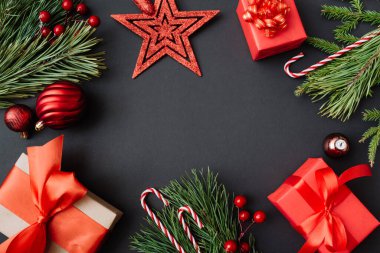 Noel kırmızı hediyeleri, dekorasyon ve siyah arka planda ağaç dalları. Yeni yıl tebrik kartı. Düz konum, üst görünüm, kopyalama alanı.