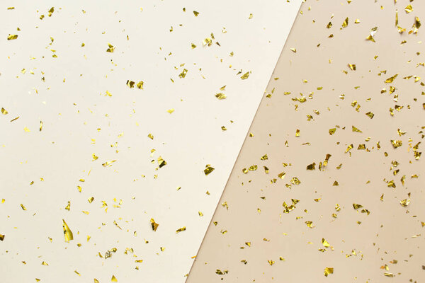 Golden confetti on beige, white paper geometric trendy background. Festive holiday backdrop. Birthday congratulations Christmas New Year. Flat lay, top view, copy space.