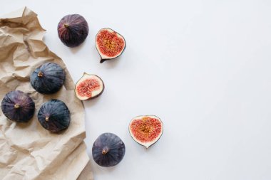 Taze dilimlenmiş ve beyaz arka planda olgun incirler. Yemek fotoğrafı geçmişi. Üst Manzara 'da dümdüz yatıyordu. Boşluğu kopyala.