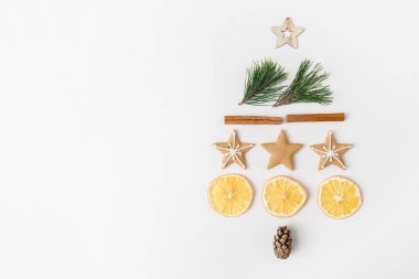Noel, kış, yeni yıl kompozisyonu. Köknar ağacı dallarından, çam kozalağından, tarçın çubuklarından, kuru portakallardan, beyaz arka planda zencefilli ekmekten oluşan yaratıcı köknar ağacı. Düz konum, üst görünüm, kopyalama alanı