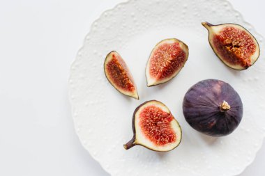 Taze dilimlenmiş ve beyaz arka planda olgun incirler. Yemek fotoğrafı geçmişi. Üst Manzara 'da dümdüz yatıyordu. Boşluğu kopyala.