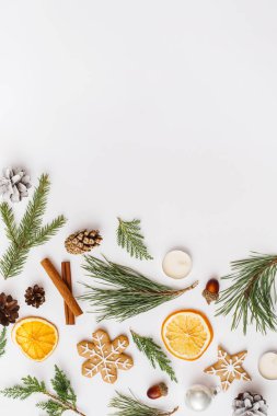 Noel, kış, yeni yıl kompozisyonu. Firavun ağacı dalları, kozalakları, kurutulmuş portakallar, tarçınlı çubuklar, zencefilli ekmek, beyaz arka planda mumlar. Düz konum, üst görünüm, kopyalama alanı