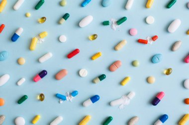 Mavi arka planda renkli hapların ve kapsüllerin yaratıcı tasarımı. Asgari tıbbi konsept. Eczacılık, Covid-19 veya Coronavirus. Düz yatış, üst görünüm