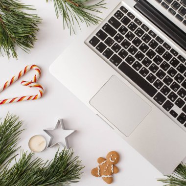 Noel, kış, yeni yıl kompozisyonu. Ofis masası çalışma alanı, firavun ağacı dalları, zencefilli ekmek, şekerler, beyaz arka planda mumlar. Düz yatış, üst görünüm